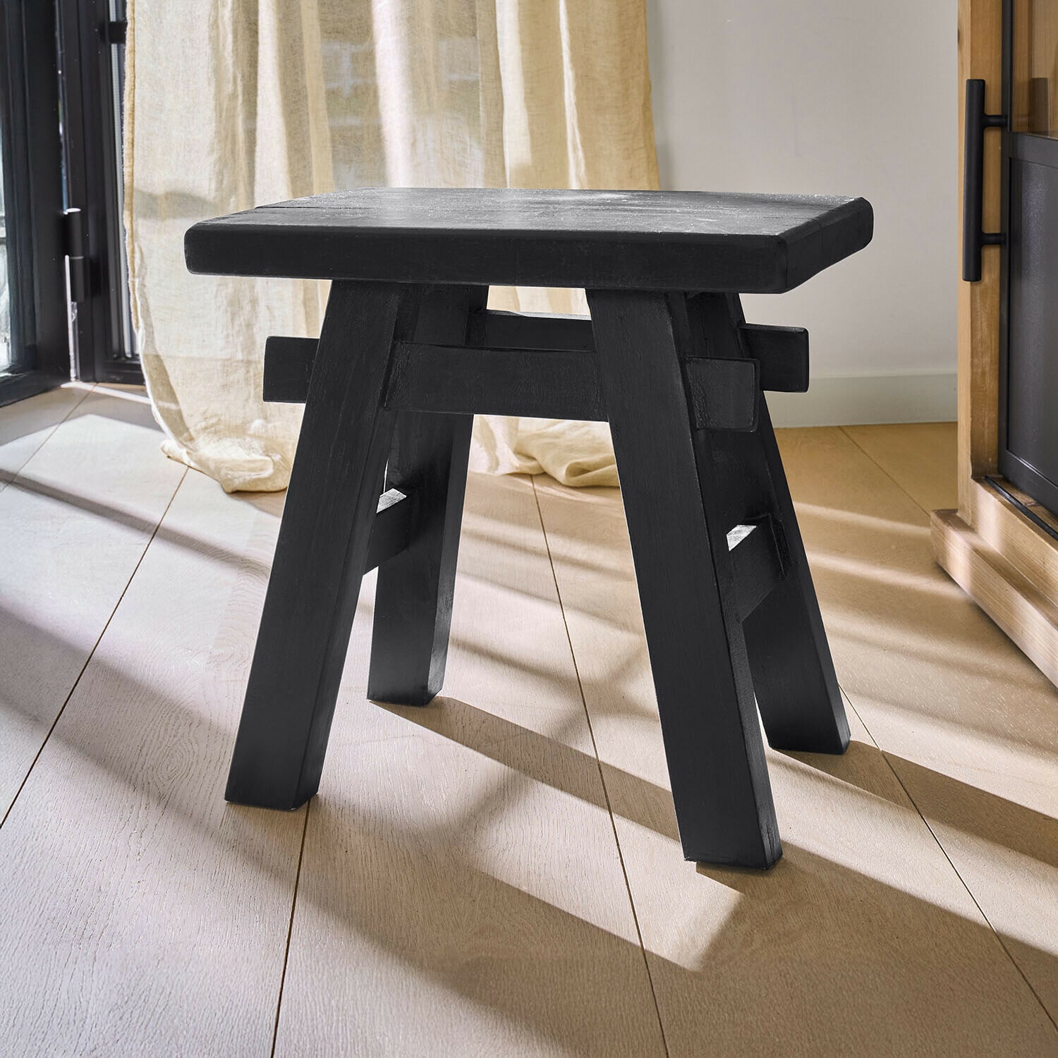 Schwarzer Holzschemel mit schlichtem Design auf hellem Boden, Möbelstück für Innenräume