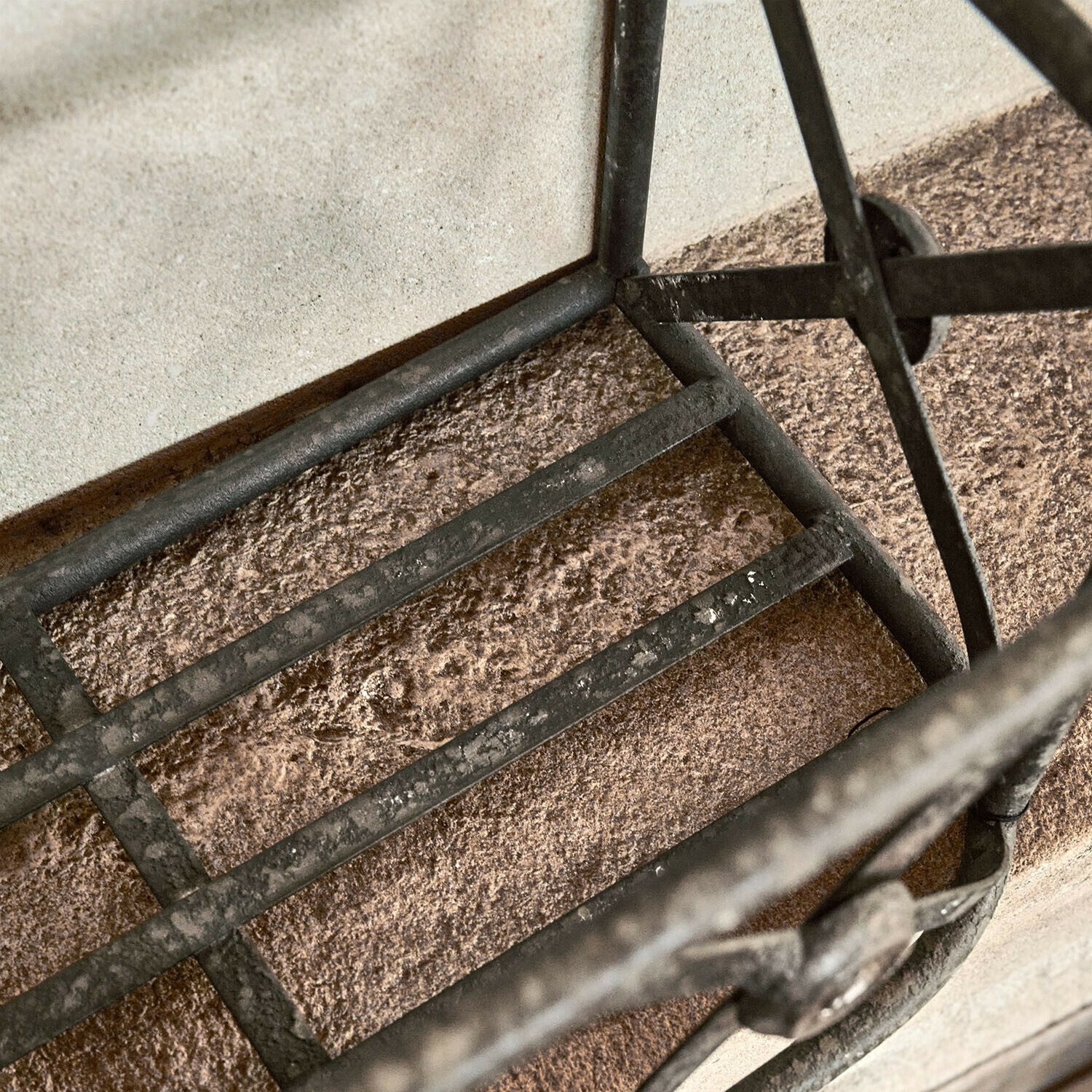 Schwarzes Metallgitter mit Roststruktur auf steinernem Untergrund