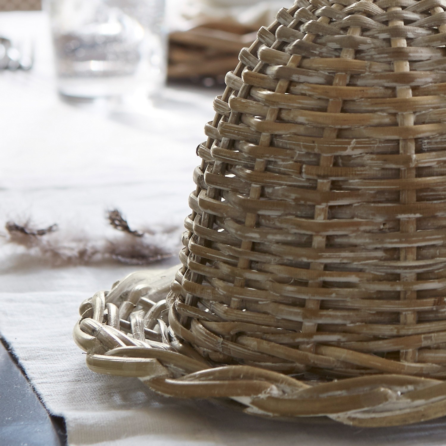 Dekorativer Korb aus natürlichem Rattan in Beige auf Tisch, rustikales Wohnaccessoire