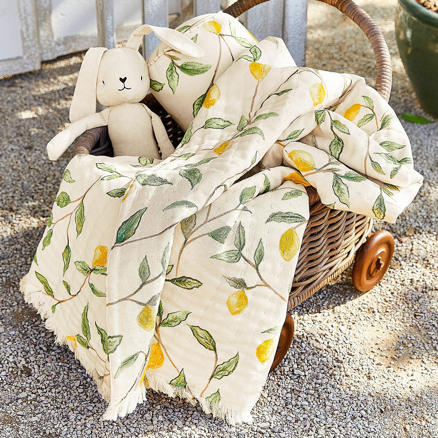 Plaid Palerina Baumwoll-Decke in Creme mit gelben Zitronen und grünen Blättern im Korb aus Rattan