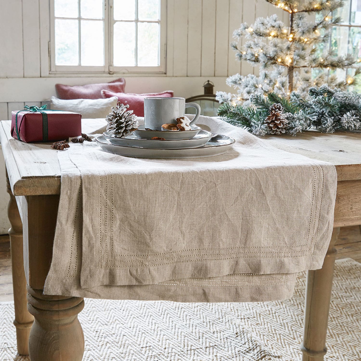 Tischläufer Brion Beiger Leinen-Tischläufer auf Holztisch mit Weihnachtsdeko und grauem Geschirr