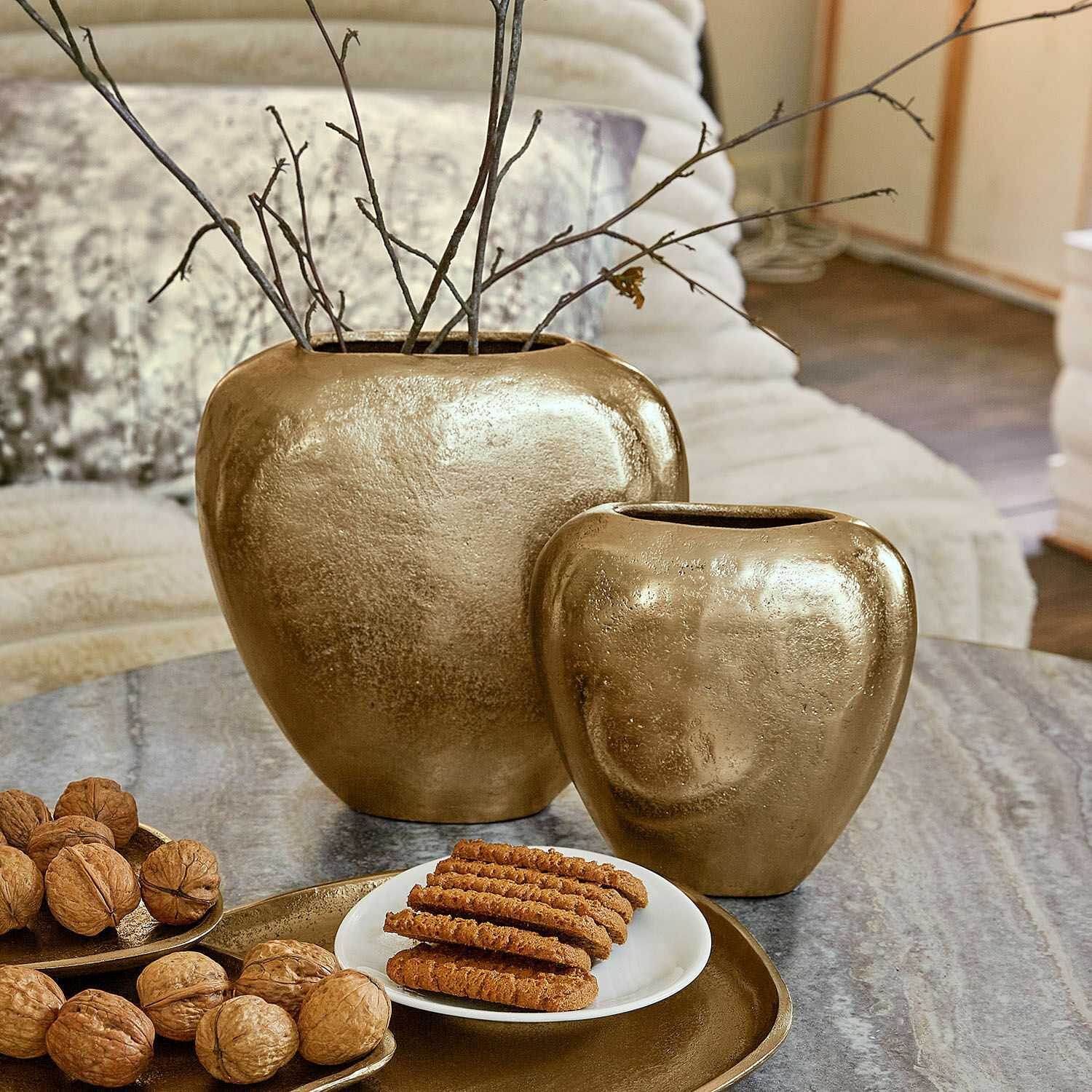 Vase 2er Set Cezelle Set aus zwei goldfarbenen Keramikvasen auf Tisch mit Nüssen und Keksen im Wohnzimmer