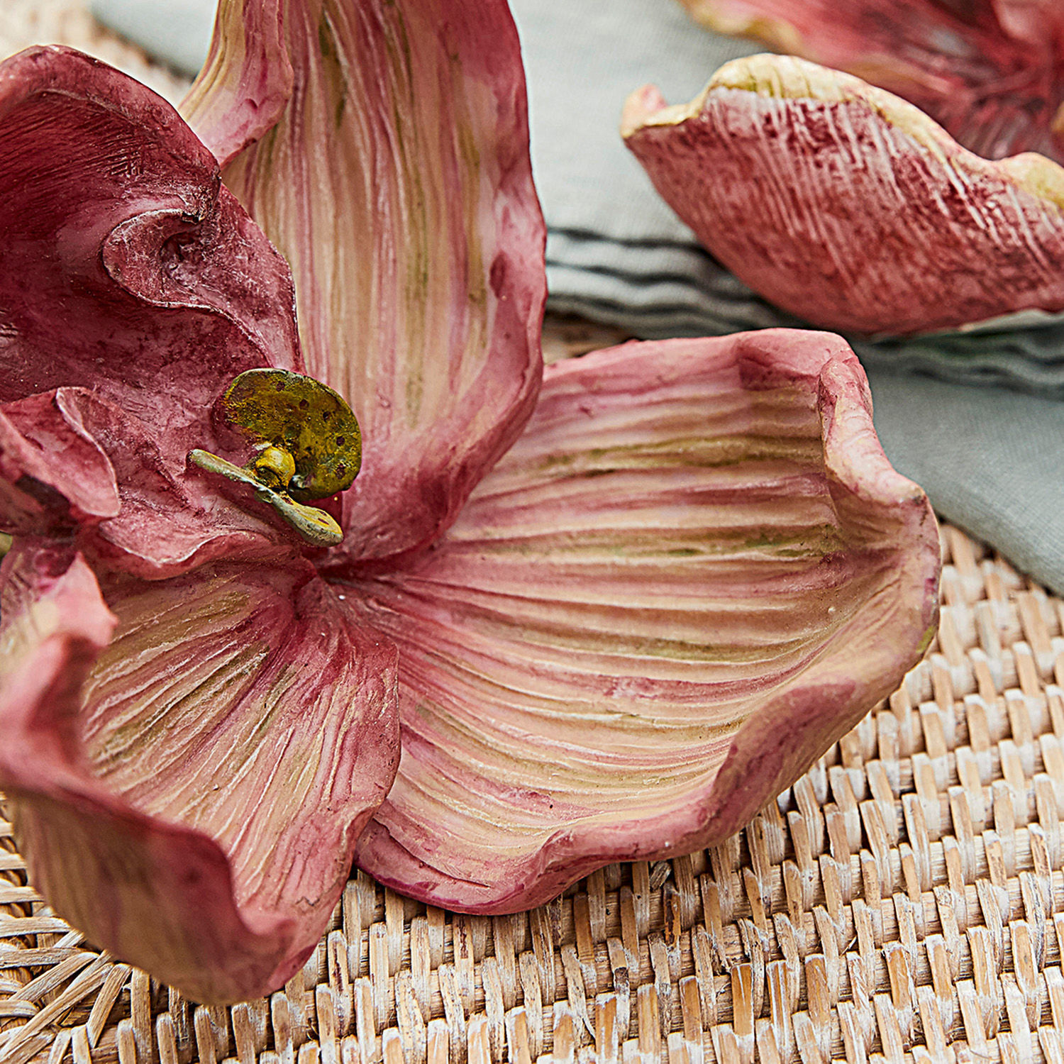 Dekorative Keramikblume in Rosa- und Grüntönen auf geflochtenem Untergrund für Innenräume