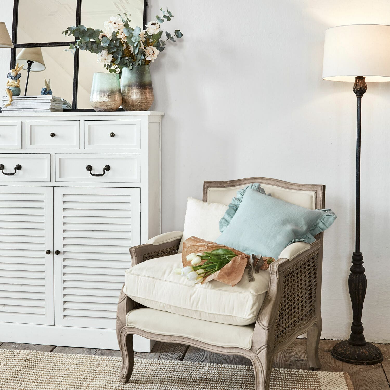 Klassischer Holz- und Stoffsessel in Creme mit Kissen und Tulpenstrauß im gemütlichen Wohnzimmer