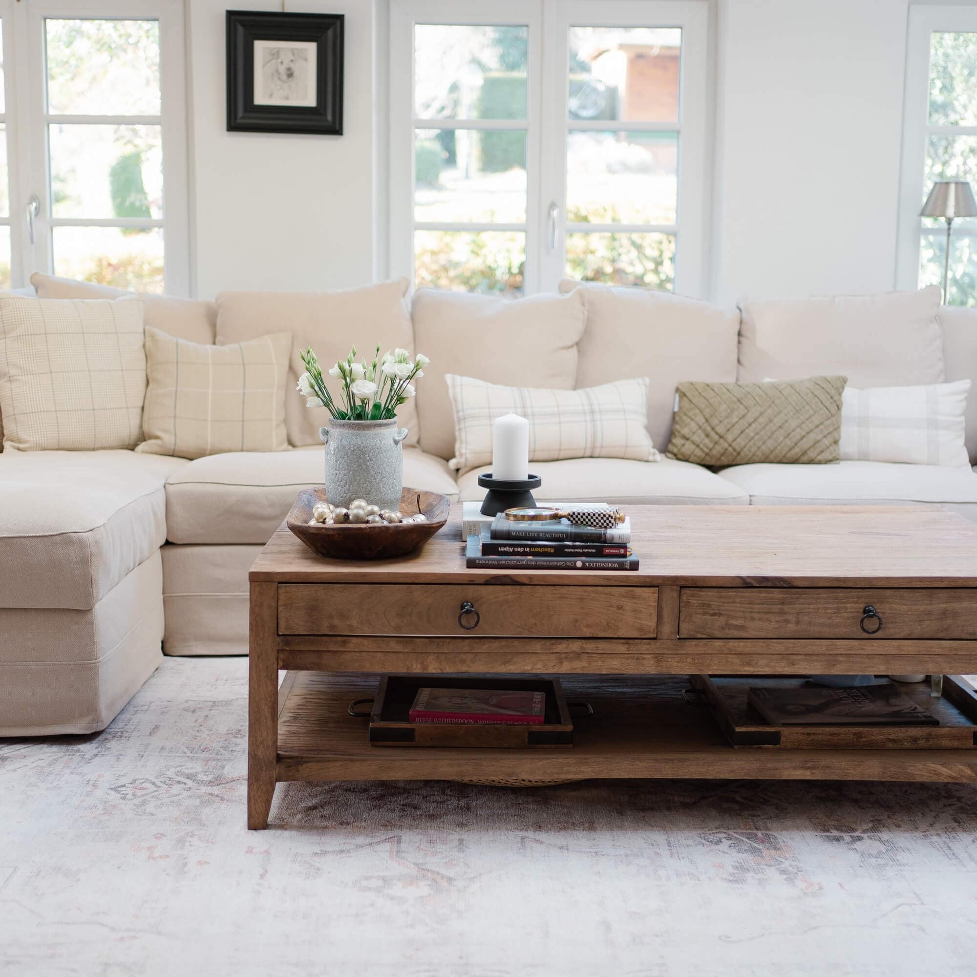 Holz-Couchtisch mit Schubladen und Dekoration vor hellem Sofa im Wohnzimmer