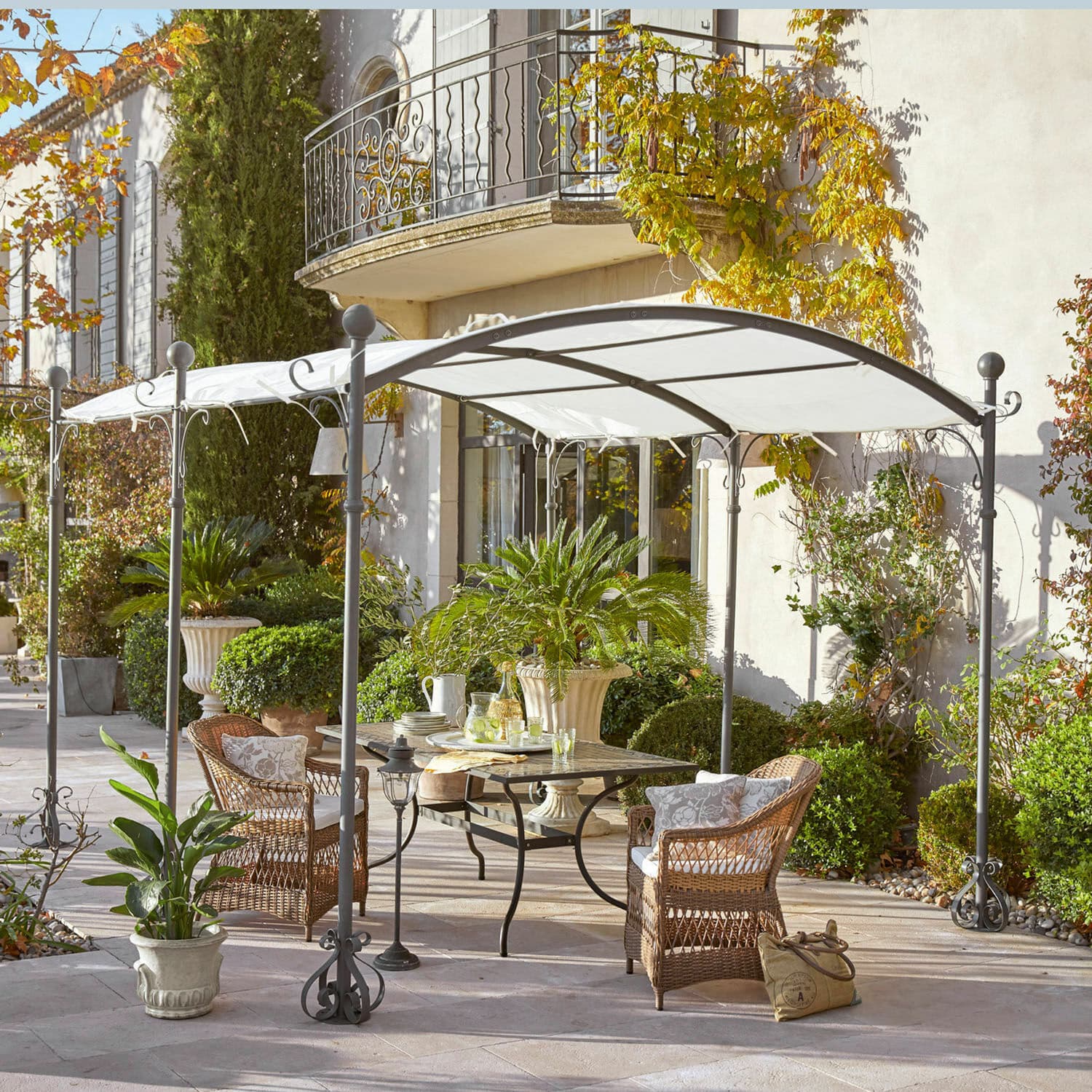 Metall-Pavillon mit weißem Dach und Korbsesseln auf Terrasse mit grünen Pflanzen
