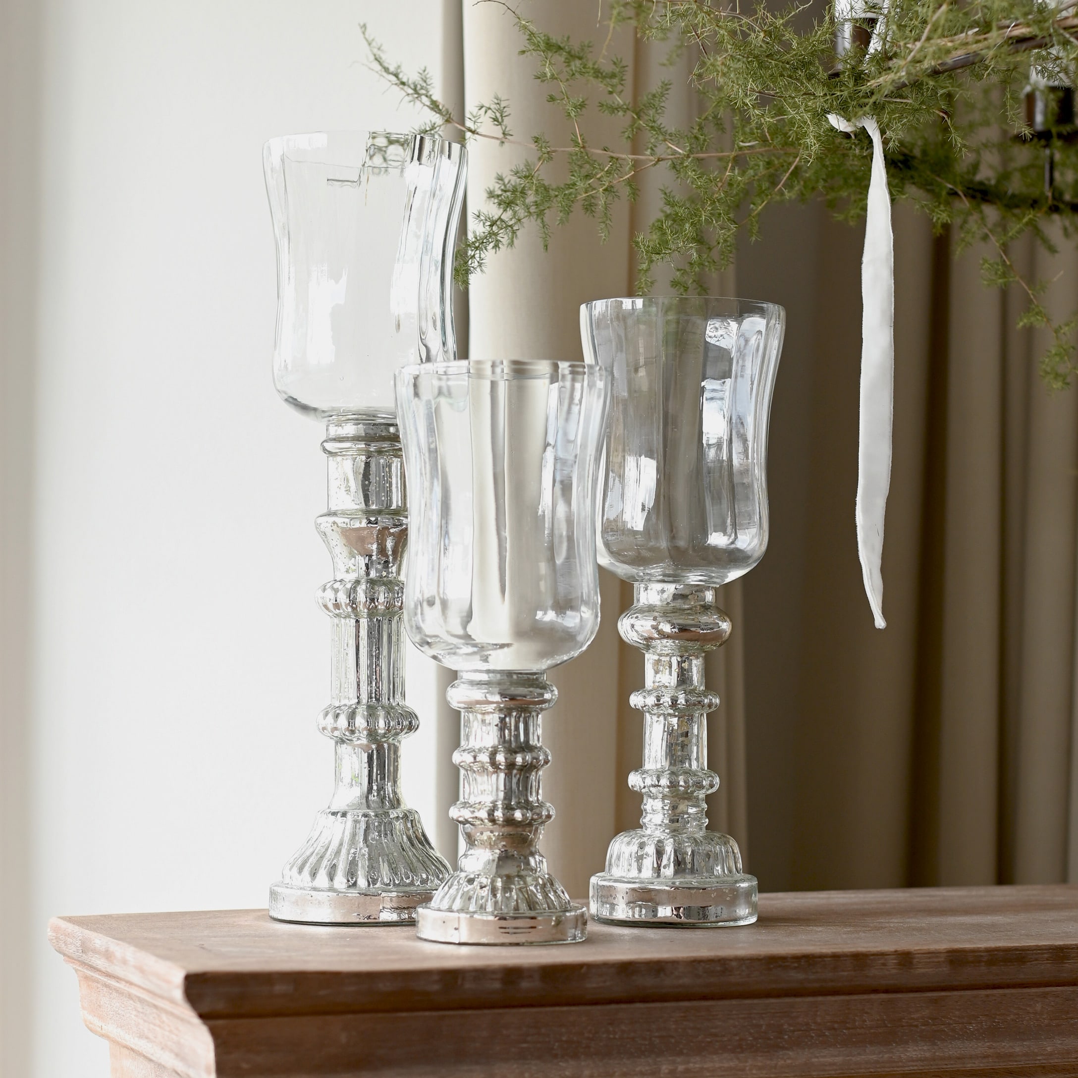 Drei dekorative Kerzenhalter aus Glas und silbernem Metall auf Holzplatte