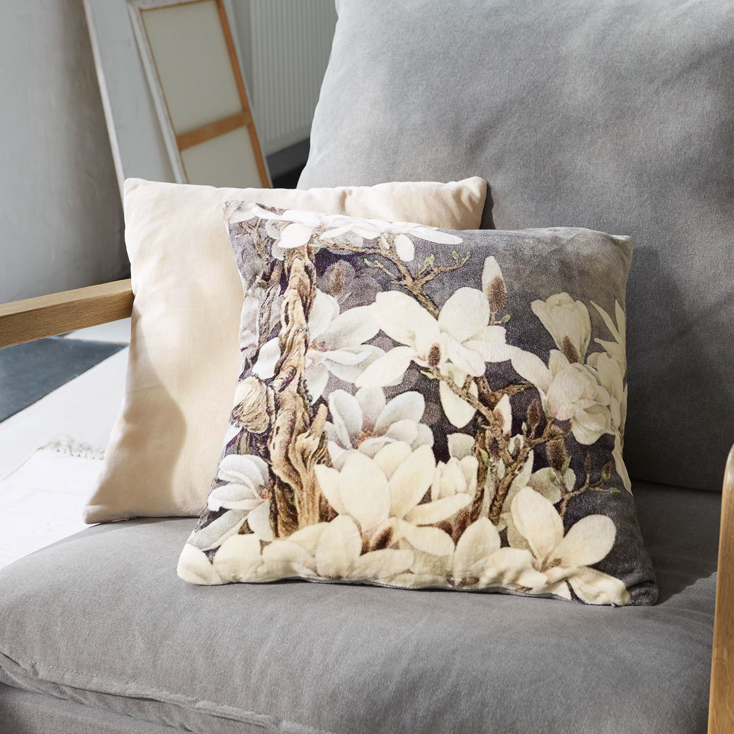 Dekoratives Kissen aus weichem Material mit floralem Muster in Beige- und Grautönen auf Sofa