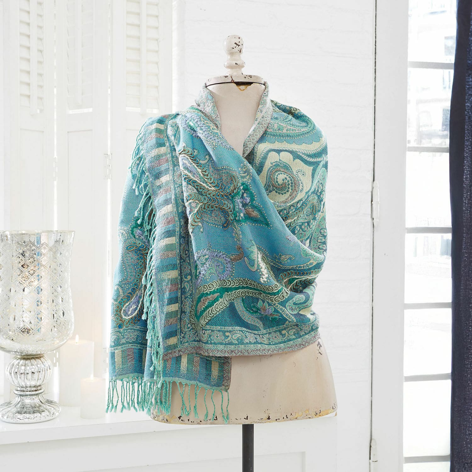 Schal Carol Türkisfarbener Paisley-Schal mit Fransen auf Schneiderpuppe in hellem Raum, Wohnaccessoire