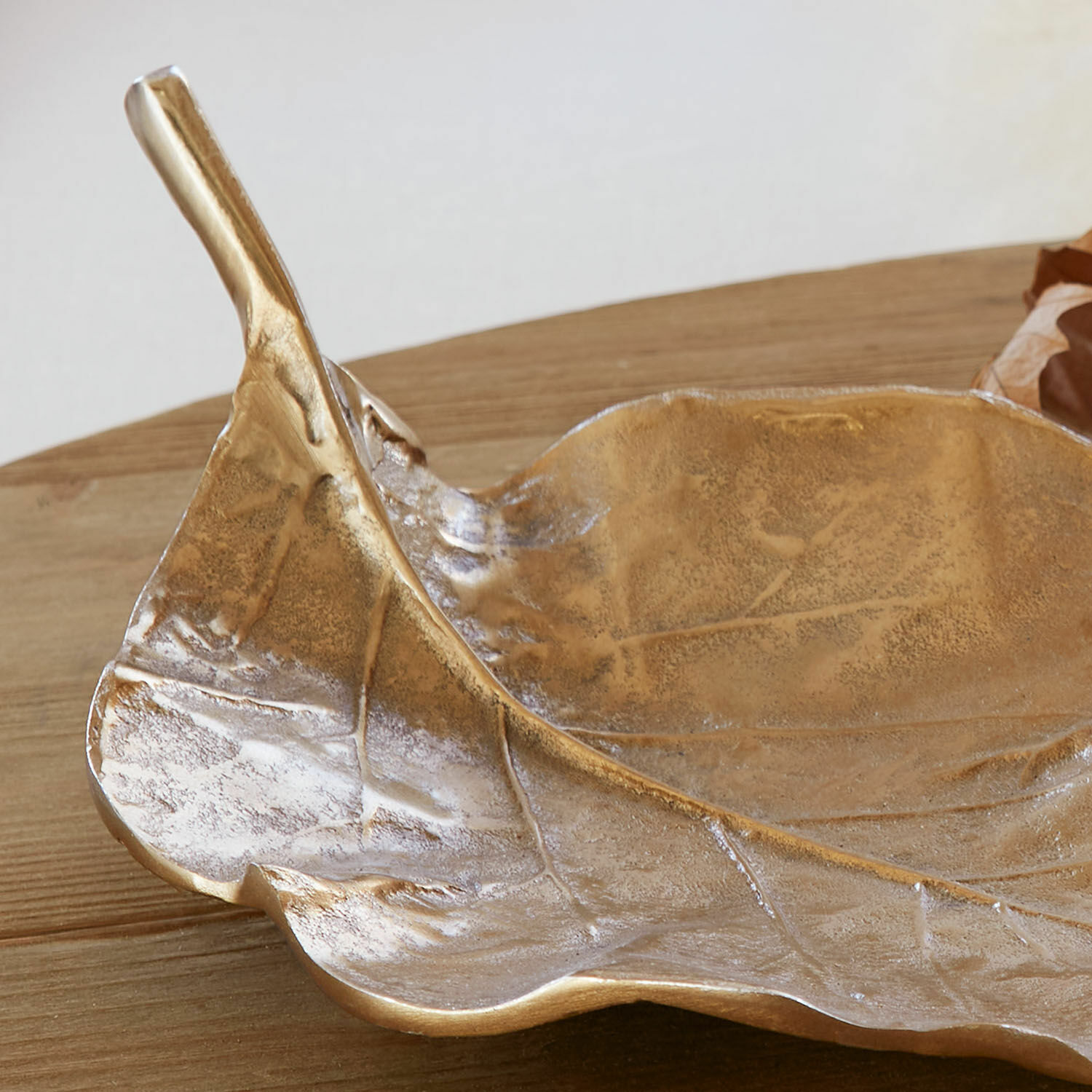 Dekorative Schale in Blattform aus goldenem Metall auf Holztisch