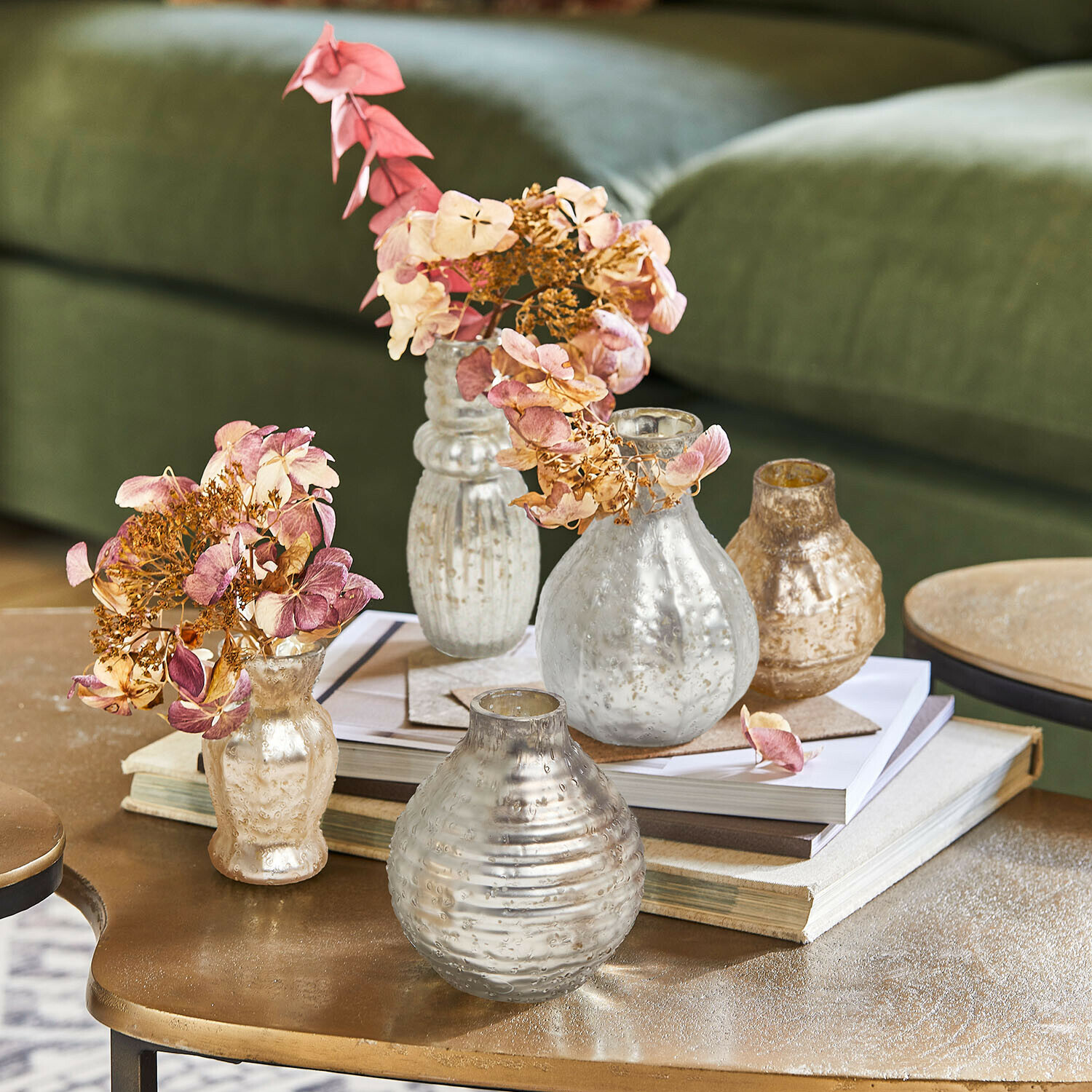 Set aus silbernen und goldenen Glasvasen mit getrockneten Blumen auf Couchtisch