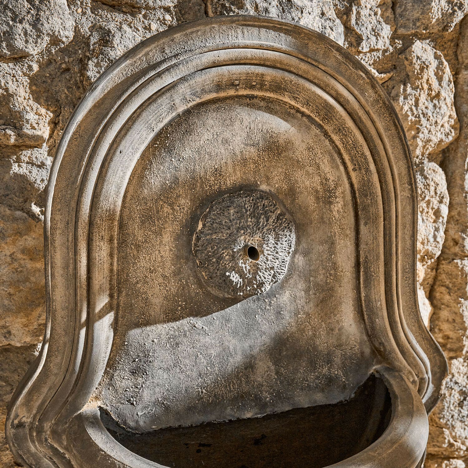 Rustikale Wandbrunnen aus Naturstein mit strukturierter Oberfläche und Wasserablaufloch