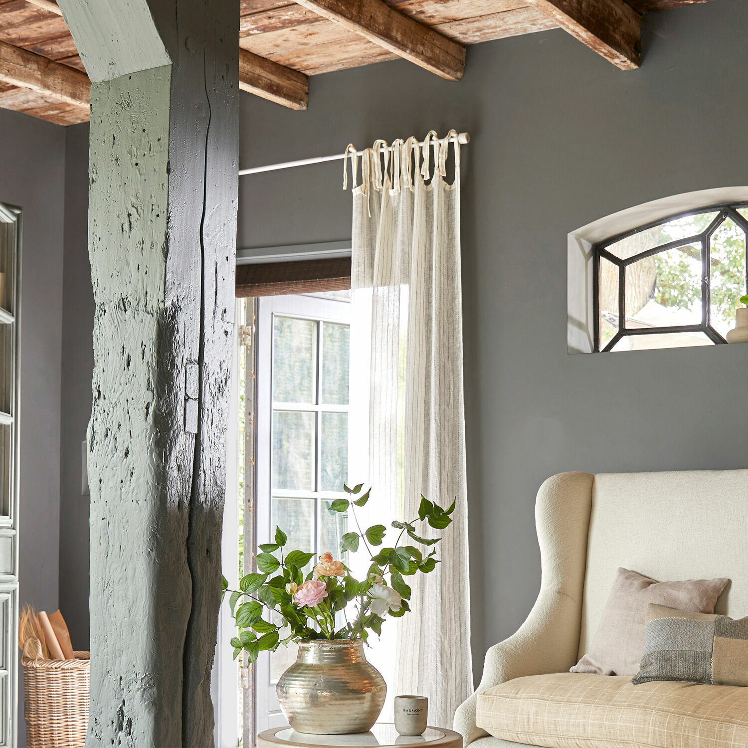 Gemütliches Wohnzimmer mit beigem Sofa, grauer Wand und dekorativem Blumenvasen auf dem Tisch