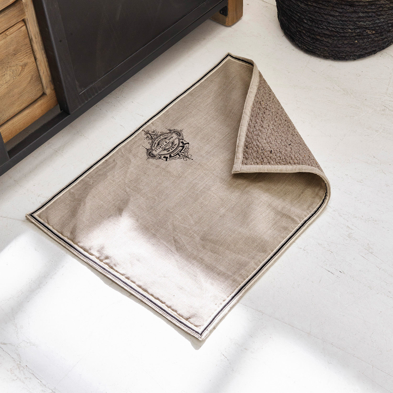 Beige Leinenmatte mit schwarzem Druck und geflochtenem Rücken auf hellem Boden