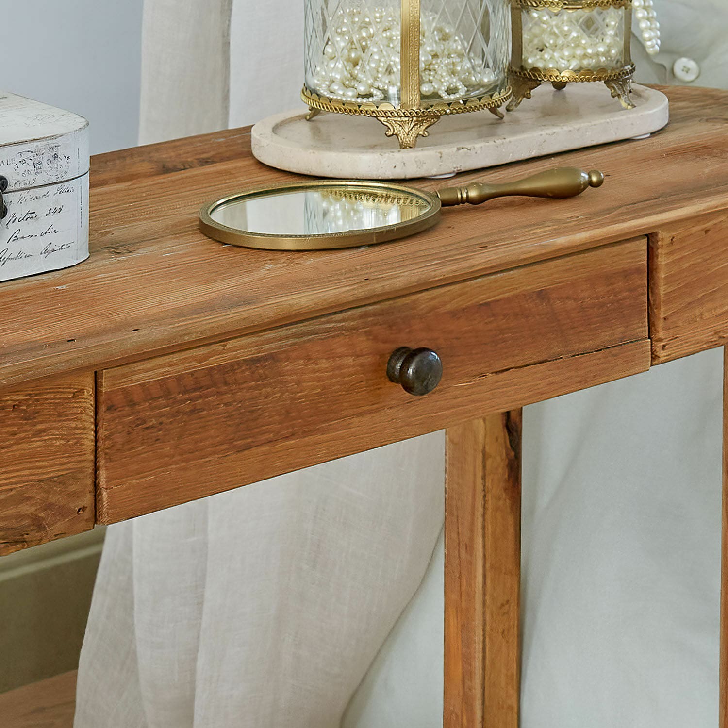 Holztisch in Naturfarbe mit Schublade, Messing-Handspiegel und Perlendekoration darauf