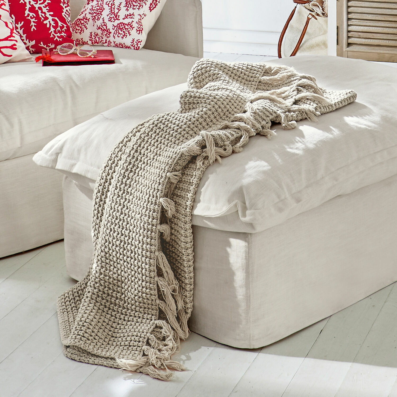 Beige gestrickte Decke mit Fransen auf hellem Sitzhocker im modernen Wohnzimmer