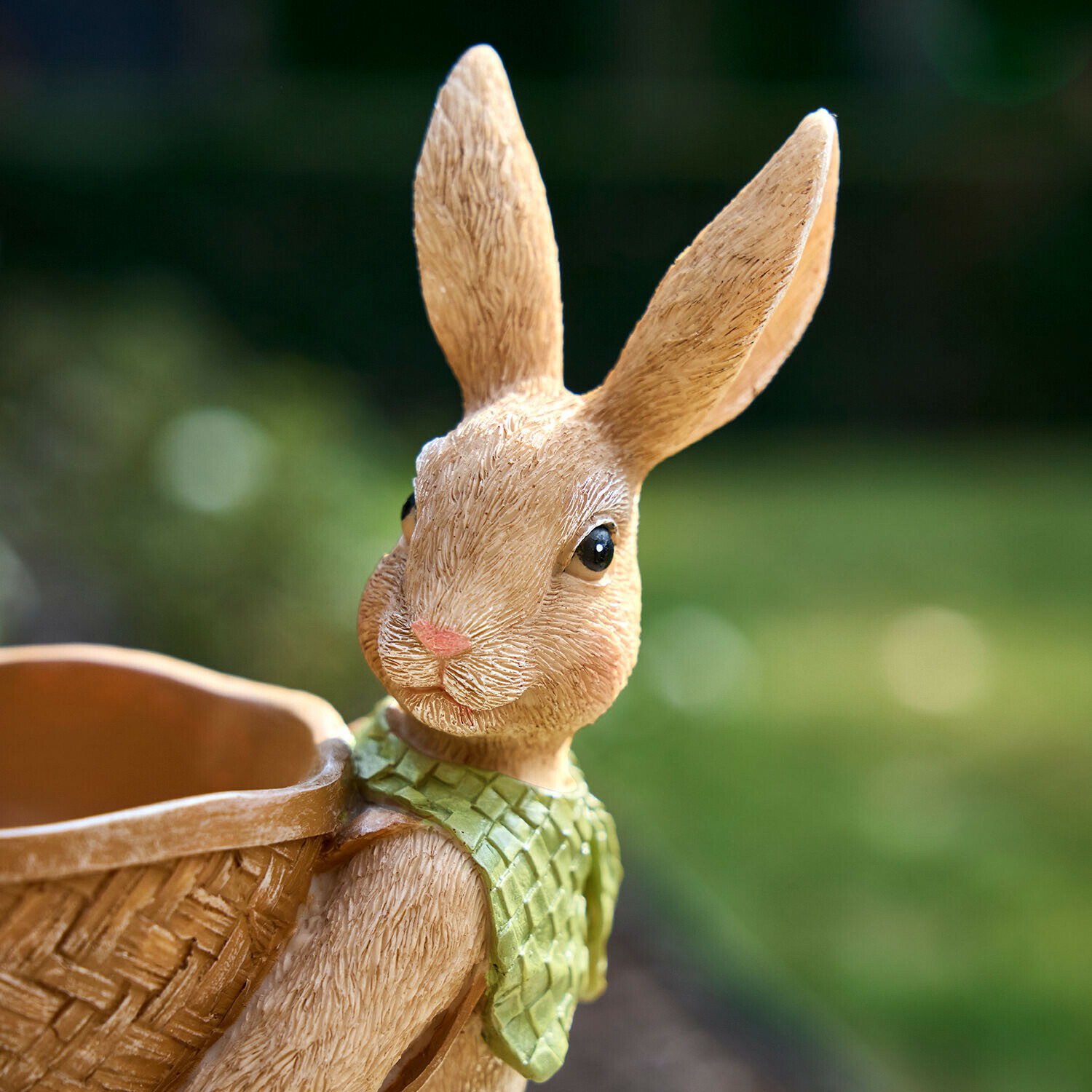 Beige Hasenfigur aus Kunststoff mit grünem Halstuch und geflochtenem Korb auf dem Rücken