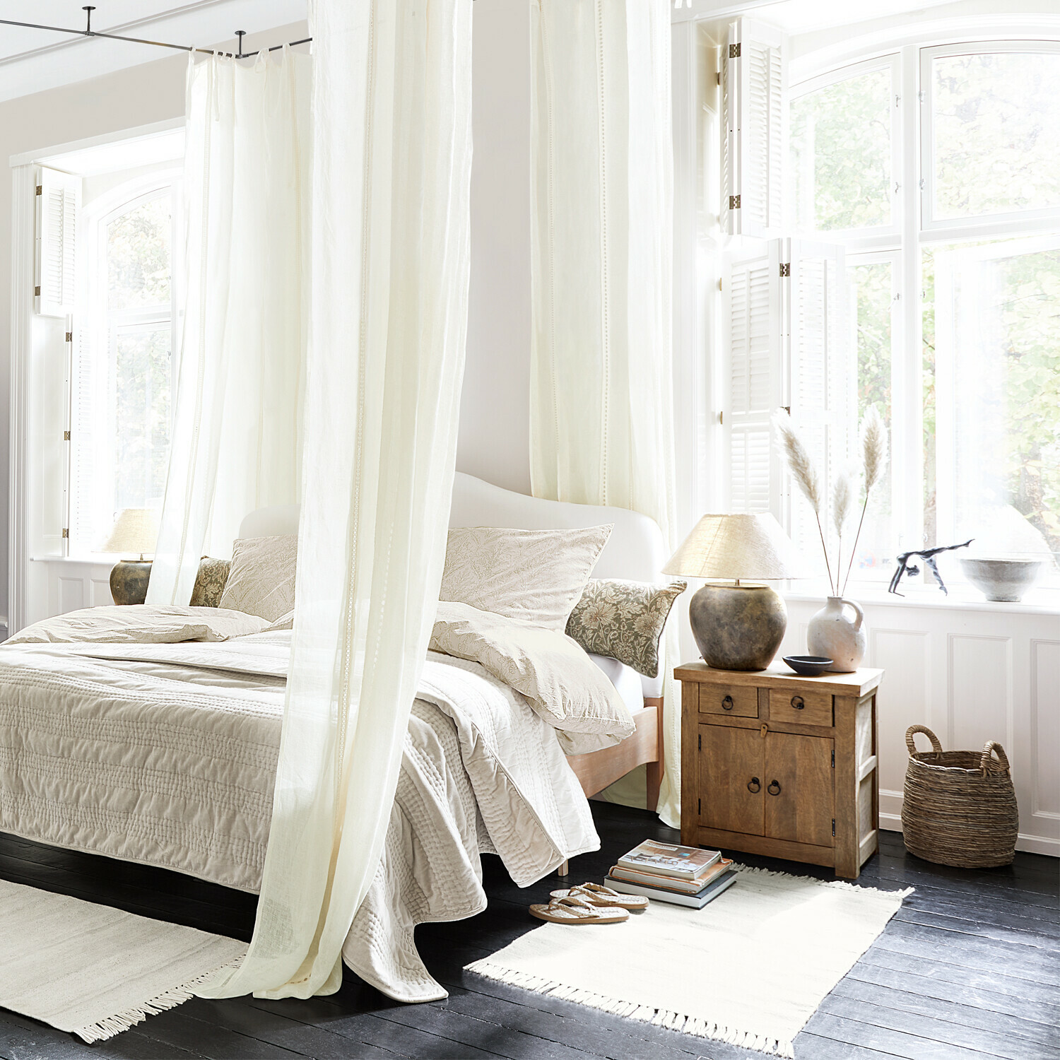 Helles Schlafzimmer mit weißer Bettwäsche und Holz-Nachttisch auf dunklem Boden