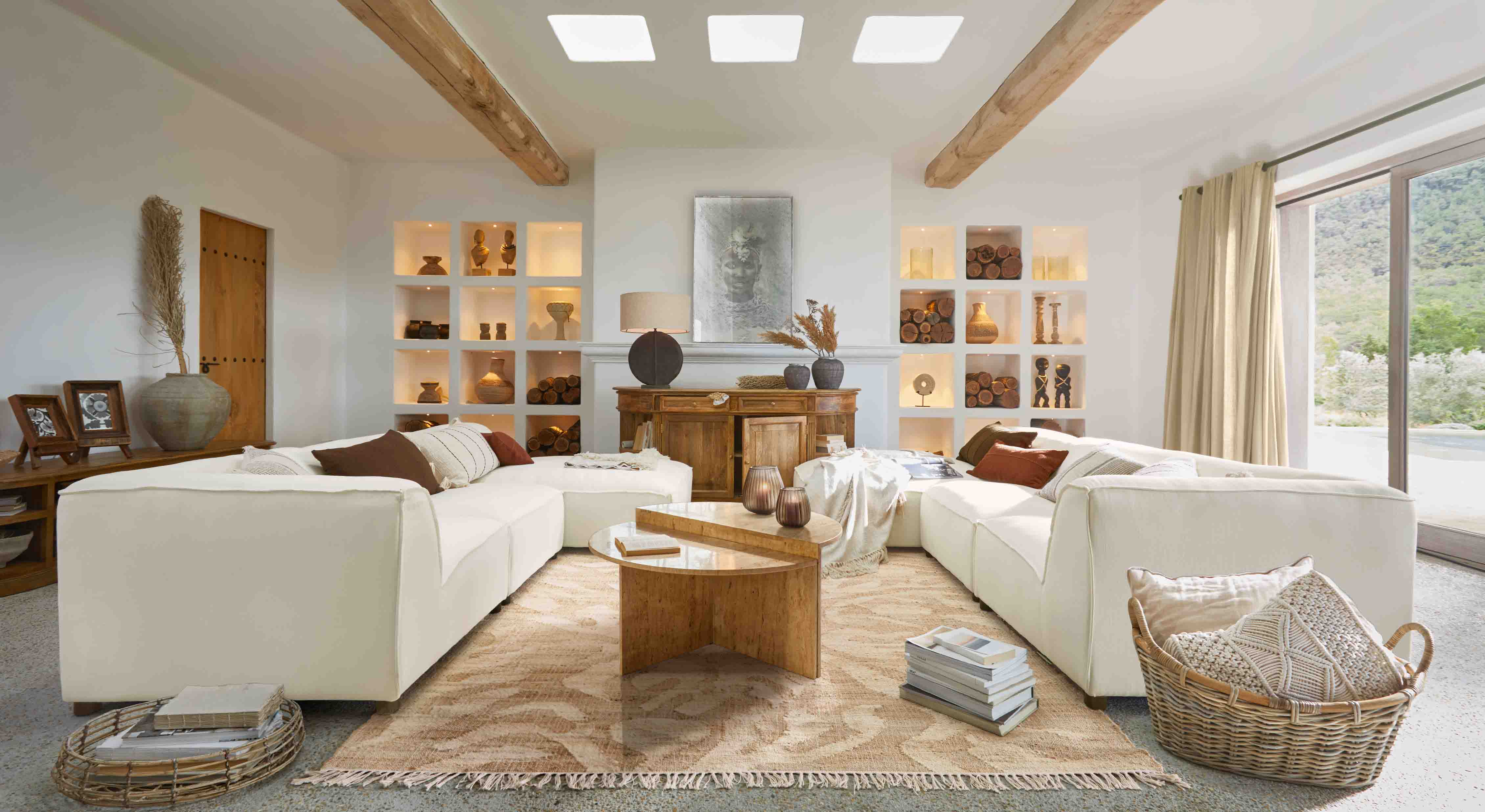 Geräumiges Wohnzimmer mit weißem Modulsofa, Holztisch und Dekorationen in Naturtönen