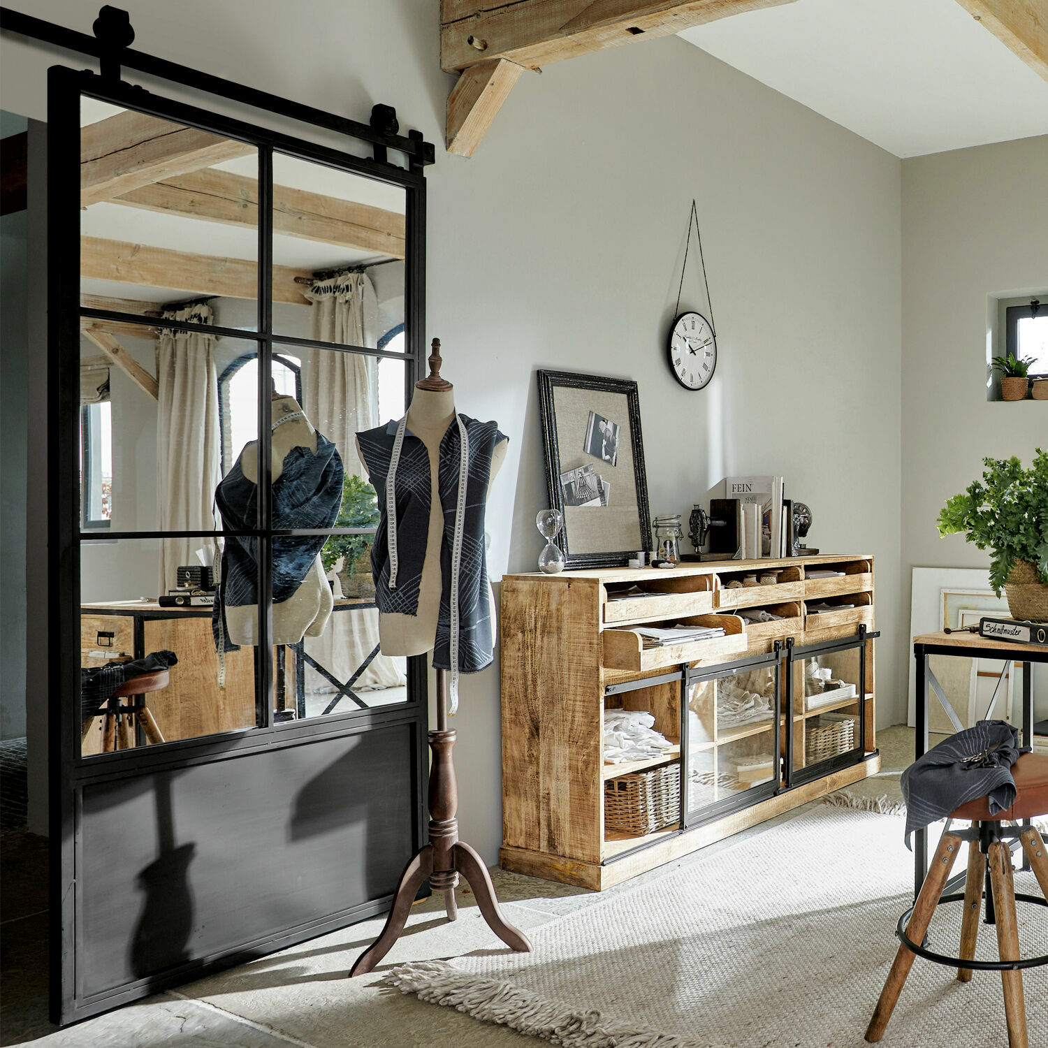 Helles Zimmer mit Holzkommode, Schneiderpuppe und schwarzer Schiebetür im Landhausstil