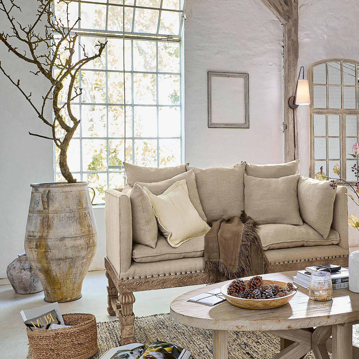 Beige Stoffsofa mit geschnitztem Holzgestell in hellem Wohnzimmer mit Dekorationen