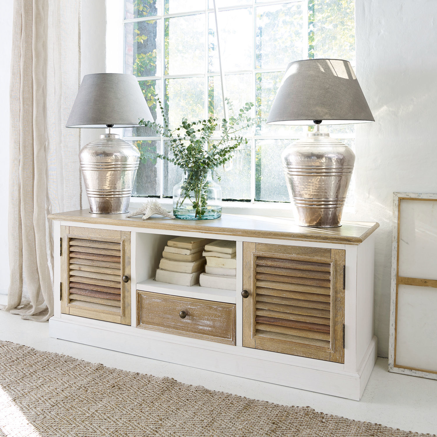 Sideboard Glencoe Weiße Holzkommode mit natürlicher Holzplatte und Lamellentüren, dekoriert mit Lampen und Büchern