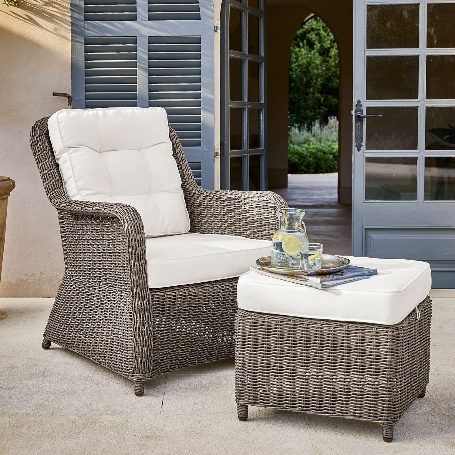 Bequemer Sessel und Hocker aus grauem Rattan mit weißen Polstern für Garten oder Terrasse