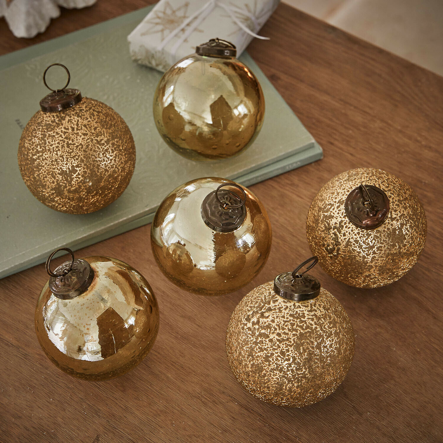 Weihnachtskugel 6er Set Fioravino Set aus sechs goldfarbenen Weihnachtskugeln aus Glas mit verschiedenen Oberflächen auf Holztisch