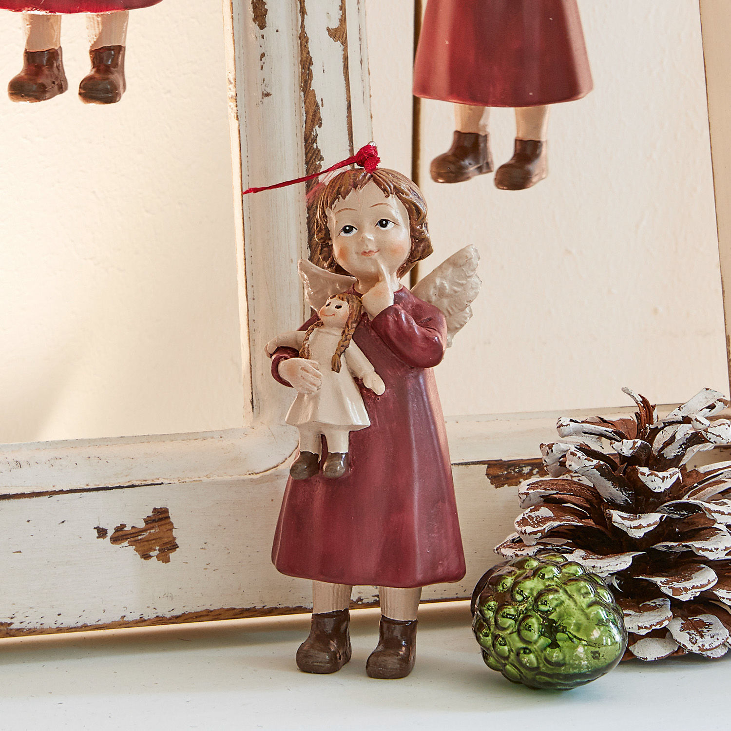 Engelsfigur aus Material in bordeauxfarbenem Kleid mit Puppe, Weihnachtsdeko mit Tannenzapfen und grünem Glas