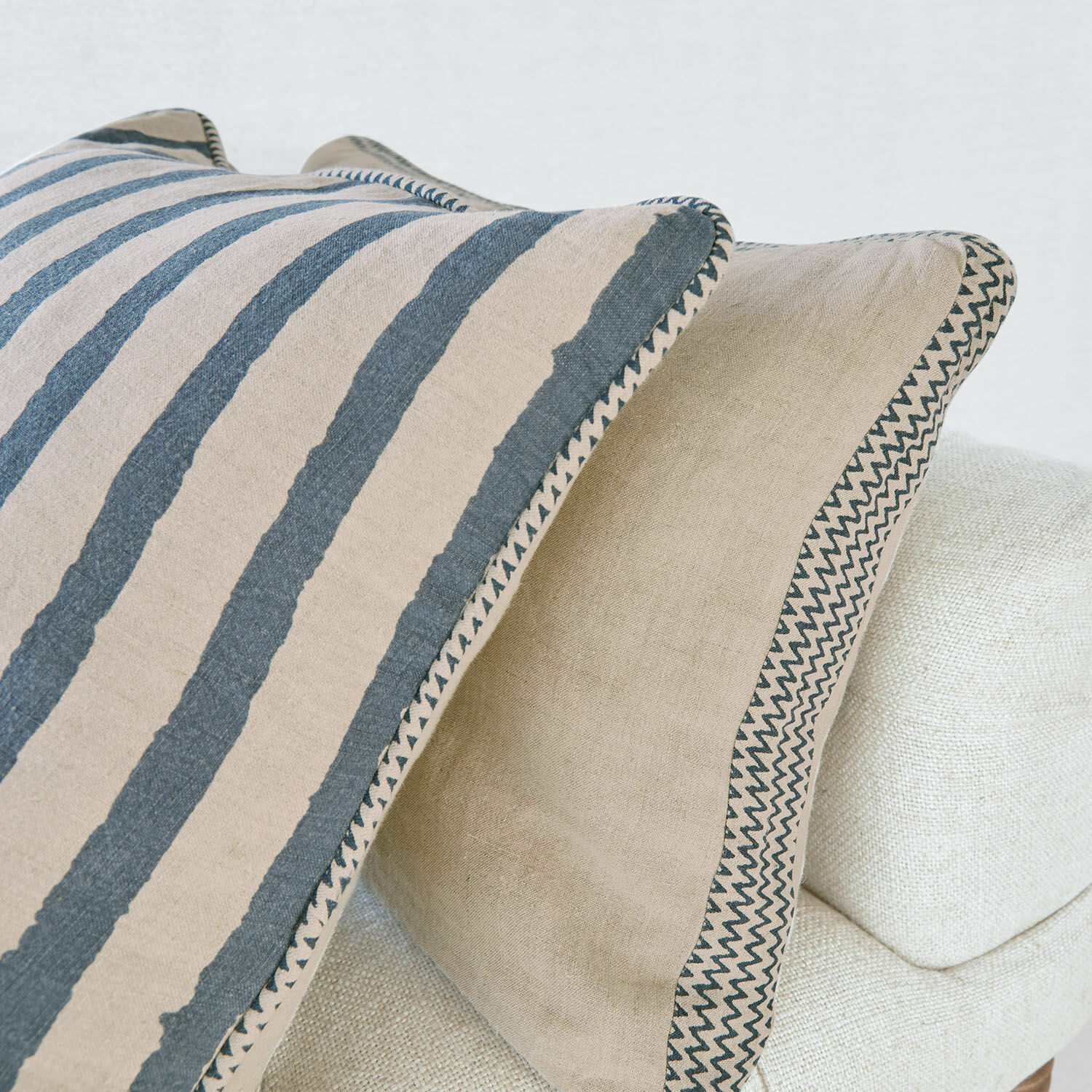 Beige-graue Leinenkissen mit geometrischem Muster auf hellem Sofa