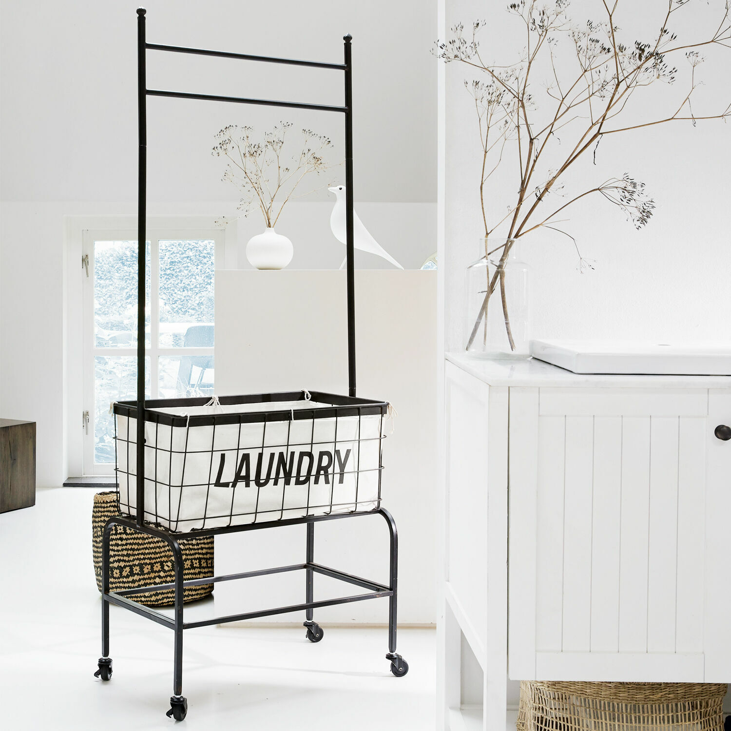 Schwarzer Metall-Wäschewagen mit weißem Stoffeinsatz und Aufschrift laundry in hellem Raum