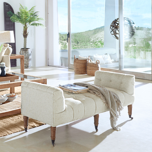 Beige gepolsterte Bank mit Holzbeinen in hellem, modernem Wohnzimmer mit großen Fenstern
