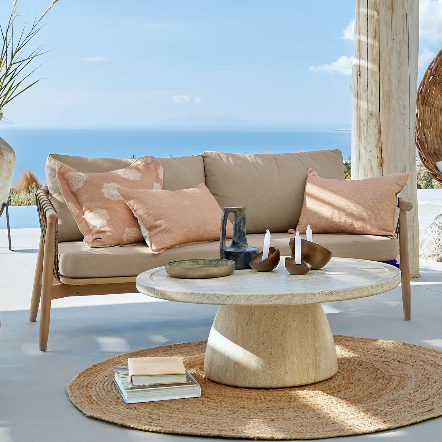Sofa FSC®-100% Thornwick Beige Sofa mit Kissen und runder Steintisch auf Terrasse mit Meerblick