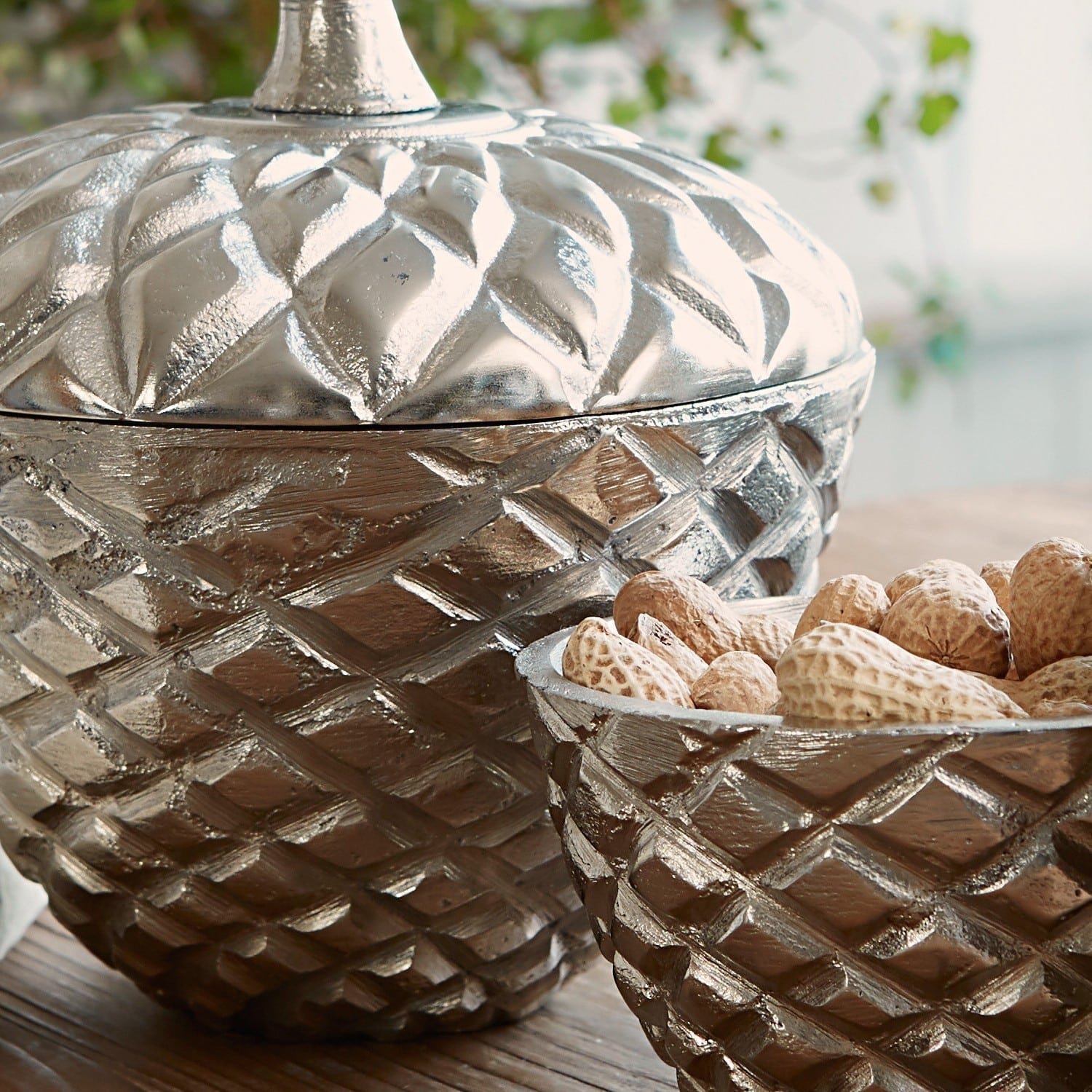 Dekorative silberne Metallschalen mit geometrischem Muster auf Holztisch, stilvolle Wohnaccessoires