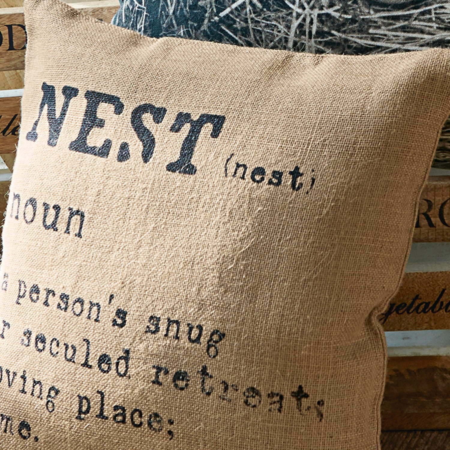 Beige Jutekissen mit schwarzem Textdruck und Nest-Motiv für gemütliche Wohnraumgestaltung