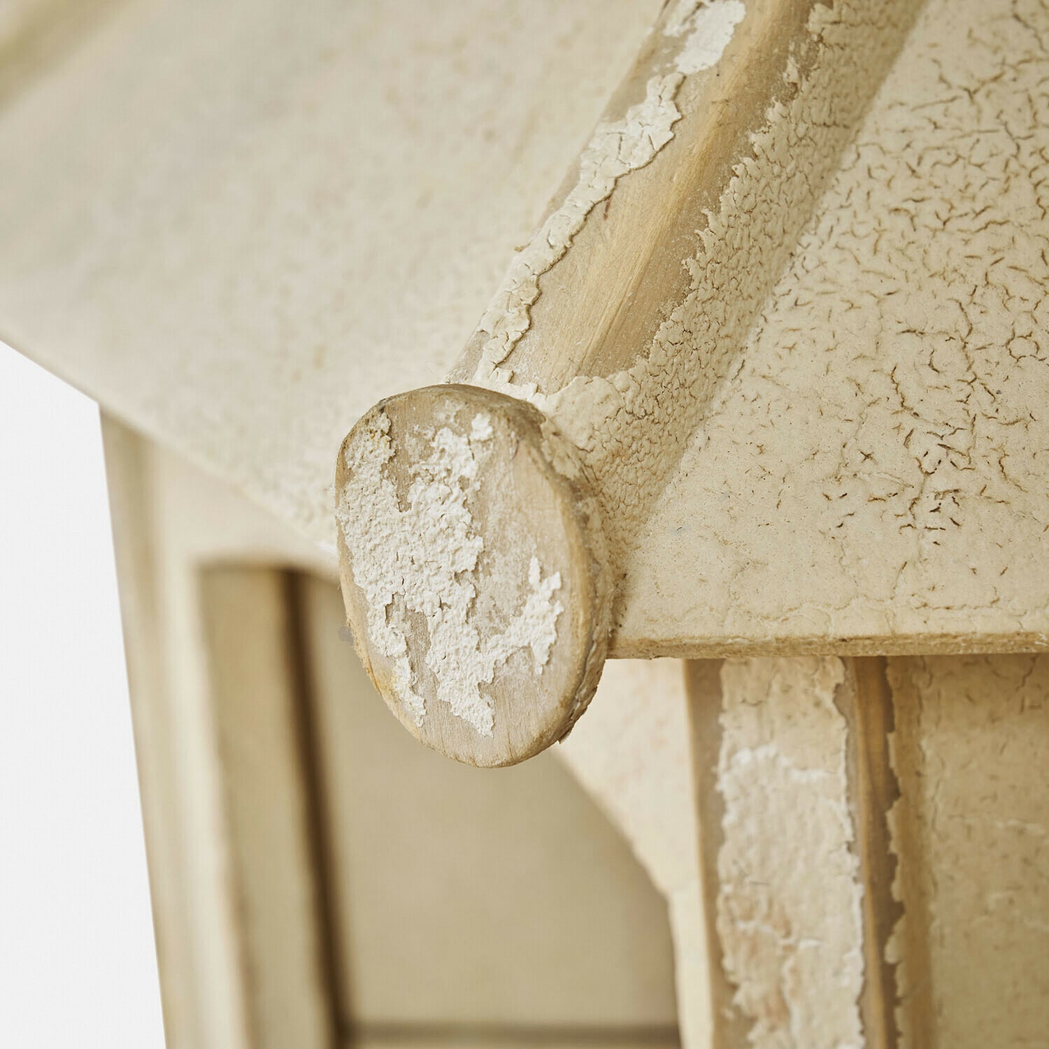 Nahaufnahme eines hölzernen Elements mit beige antikem Finish und abblätternder Farbe