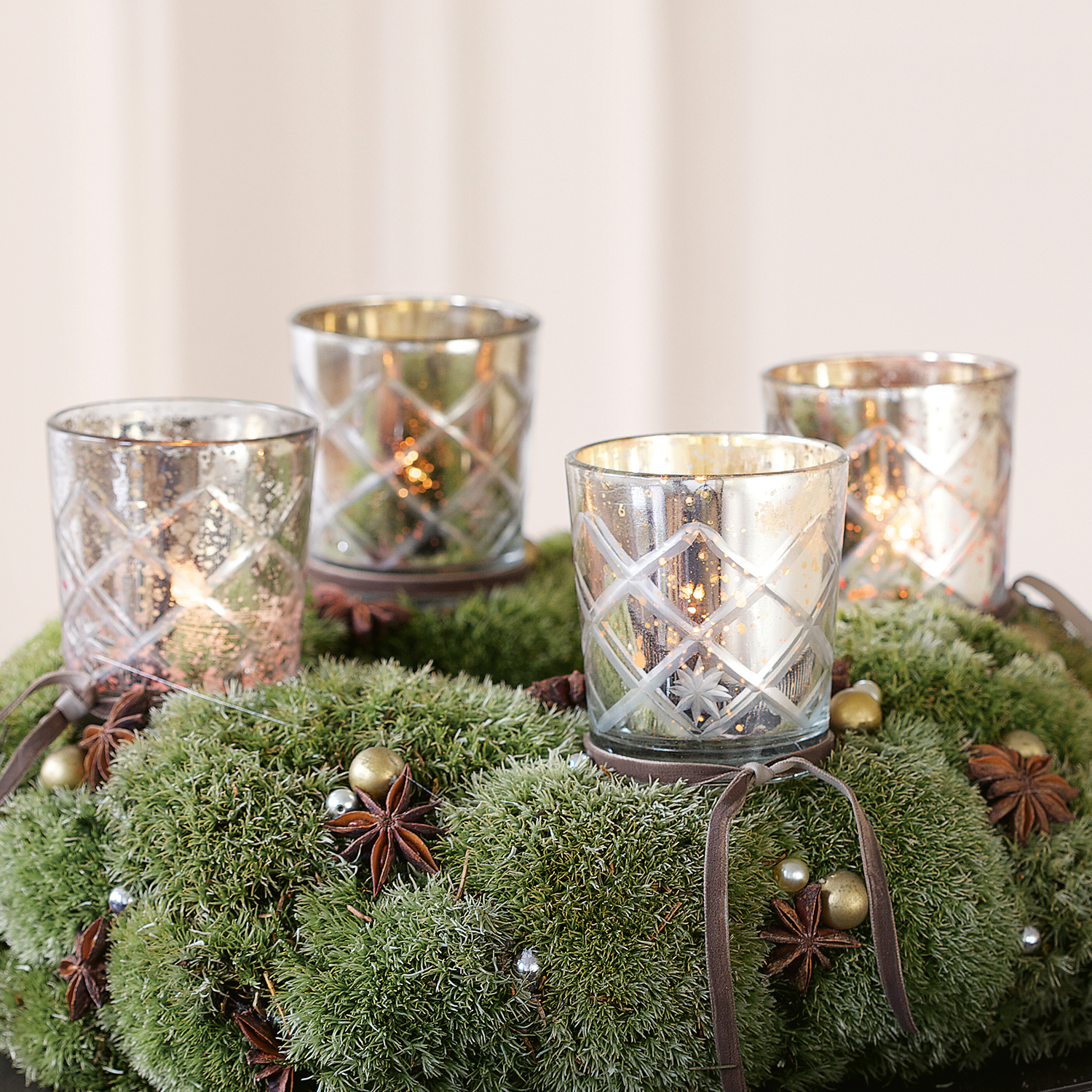 Glas-Teelichthalter mit Rautenmuster auf grünem Mooskranz mit Weihnachtsdekoration