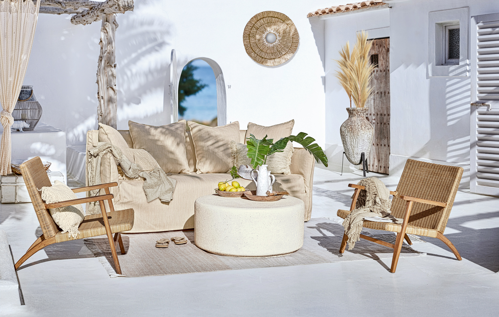 Gemütliche Boho-Gartenmöbel mit beigem Sofa und Rattanstühlen auf sonniger Terrasse