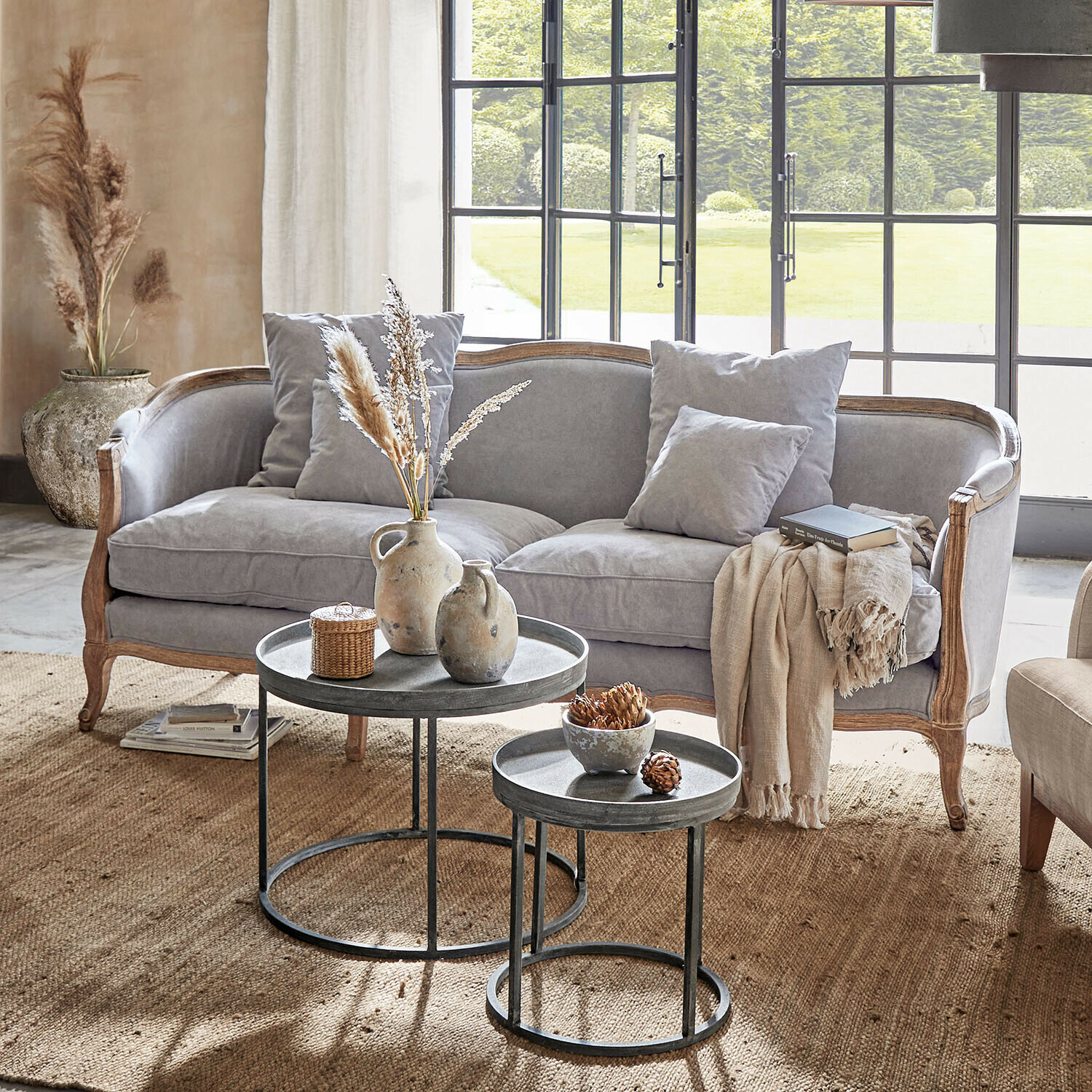 Sofa Monneville Graues Sofa mit Holzrahmen und Kissen in hellem Wohnzimmer mit Metall-Couchtischen