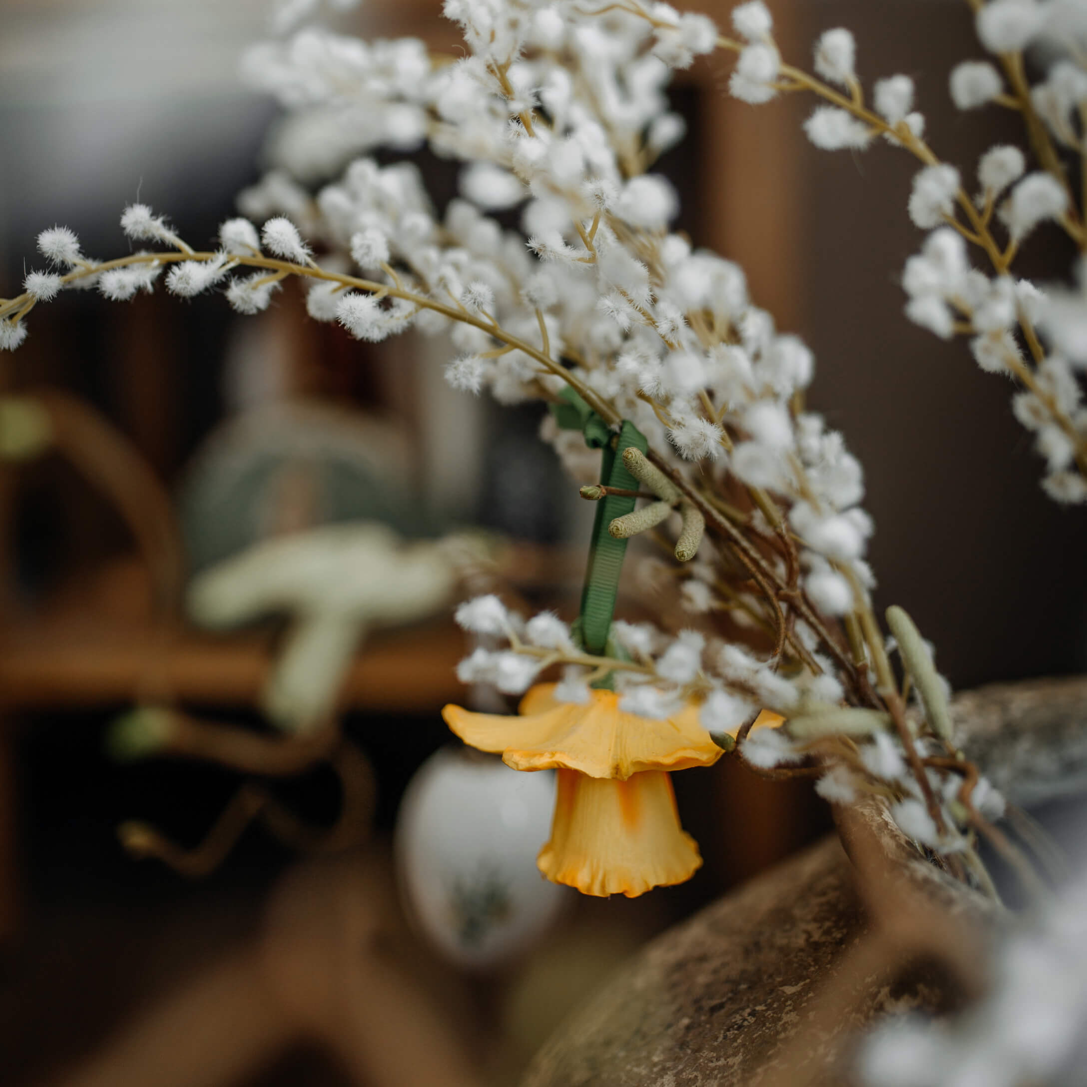 Osterdekoration mit gelber Blüte und weißen Zweigen in rustikalem Wohnambiente