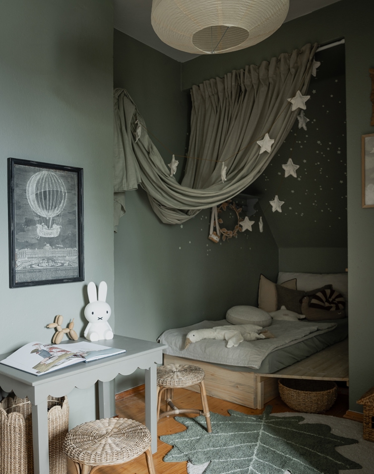 Gemütliches Kinderzimmer mit grünen Wänden, niedrigem Bett und Sternen-Dekorationen