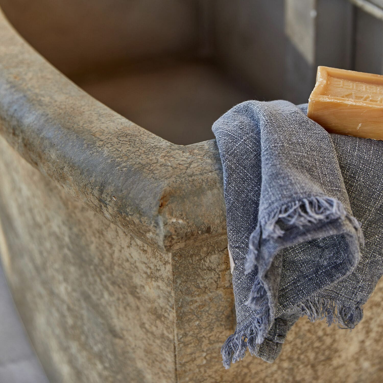 Steinbadewanne mit grauem Leinentuch und Naturseife für das Badezimmer