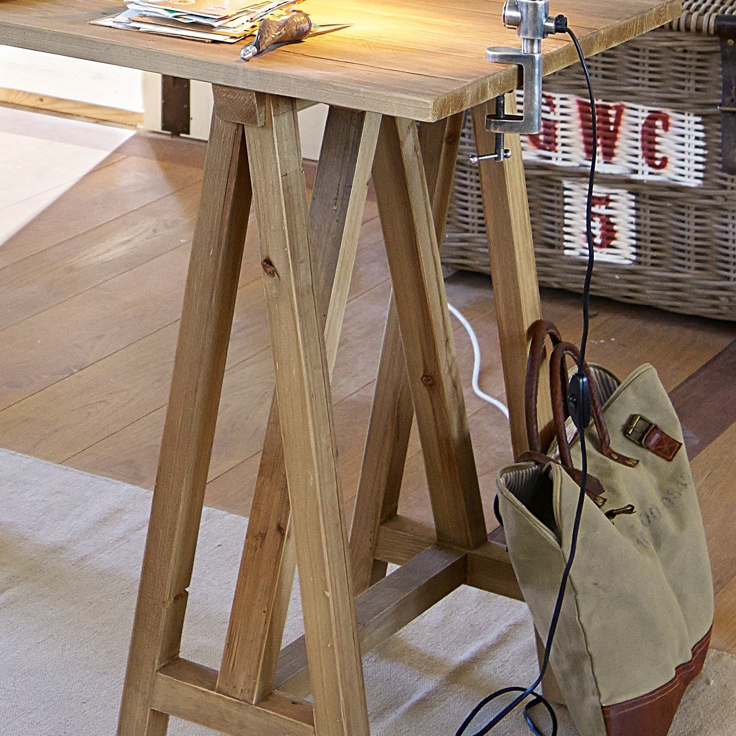 Tisch aus massivem Holz mit natürlicher Oberfläche und Vintage-Leinentasche auf dem Boden im Raum