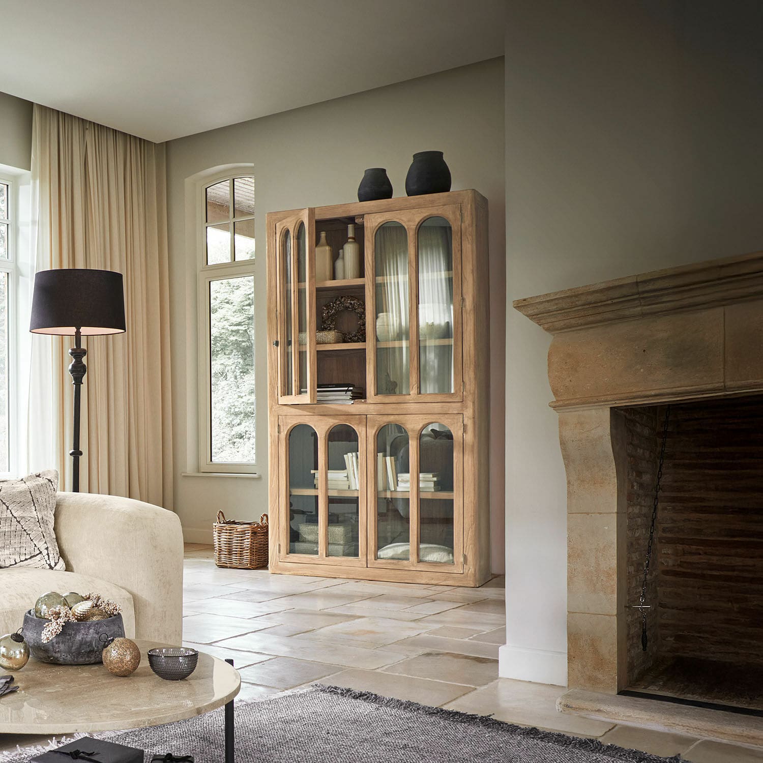 Holzvitrine mit Glastüren in natürlicher Farbe in hellem Wohnzimmer mit Steinkamin