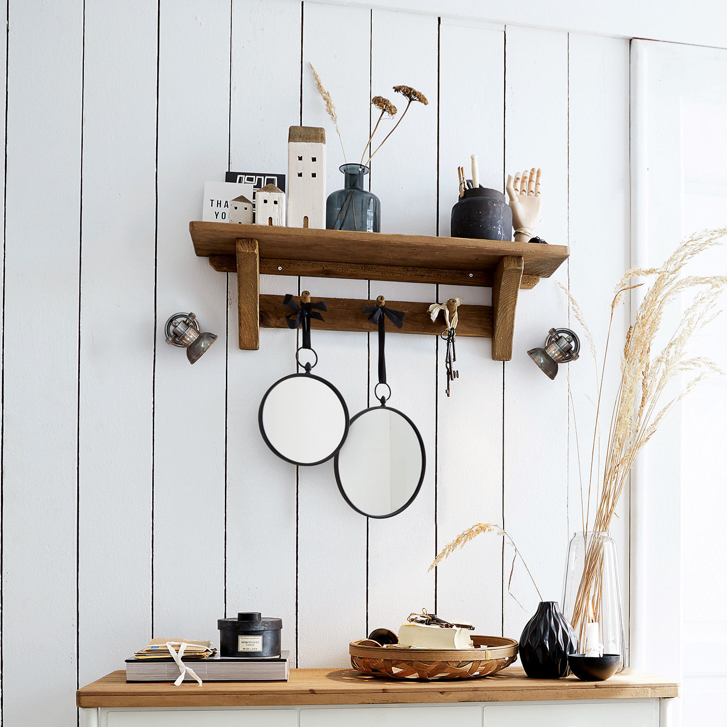 Holz-Wandregal mit Haken und zwei runden Spiegeln an weißer Wand mit Dekorationen