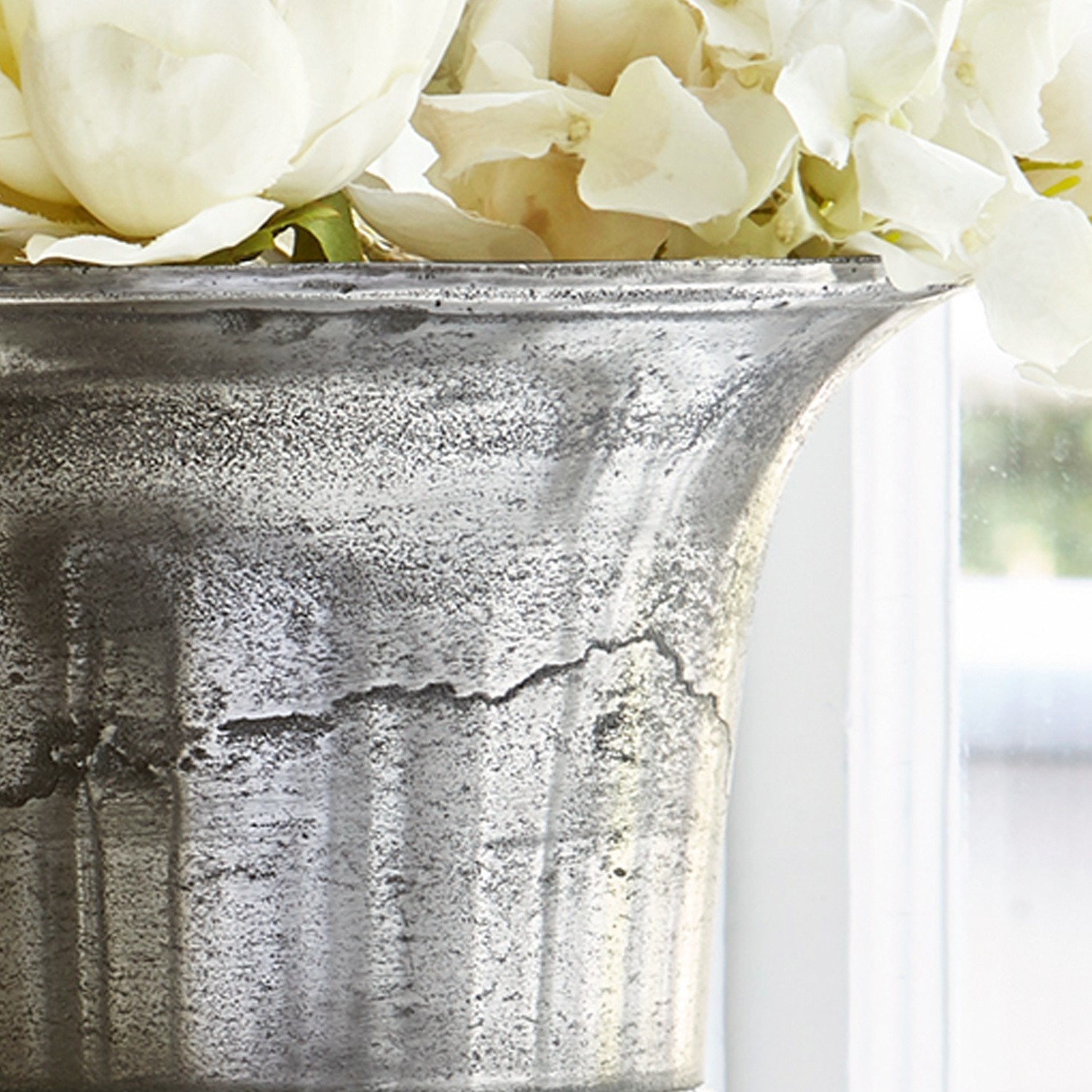 Silberne Metallblumenvase mit strukturierter Oberfläche und weißen Blumen als Dekoration