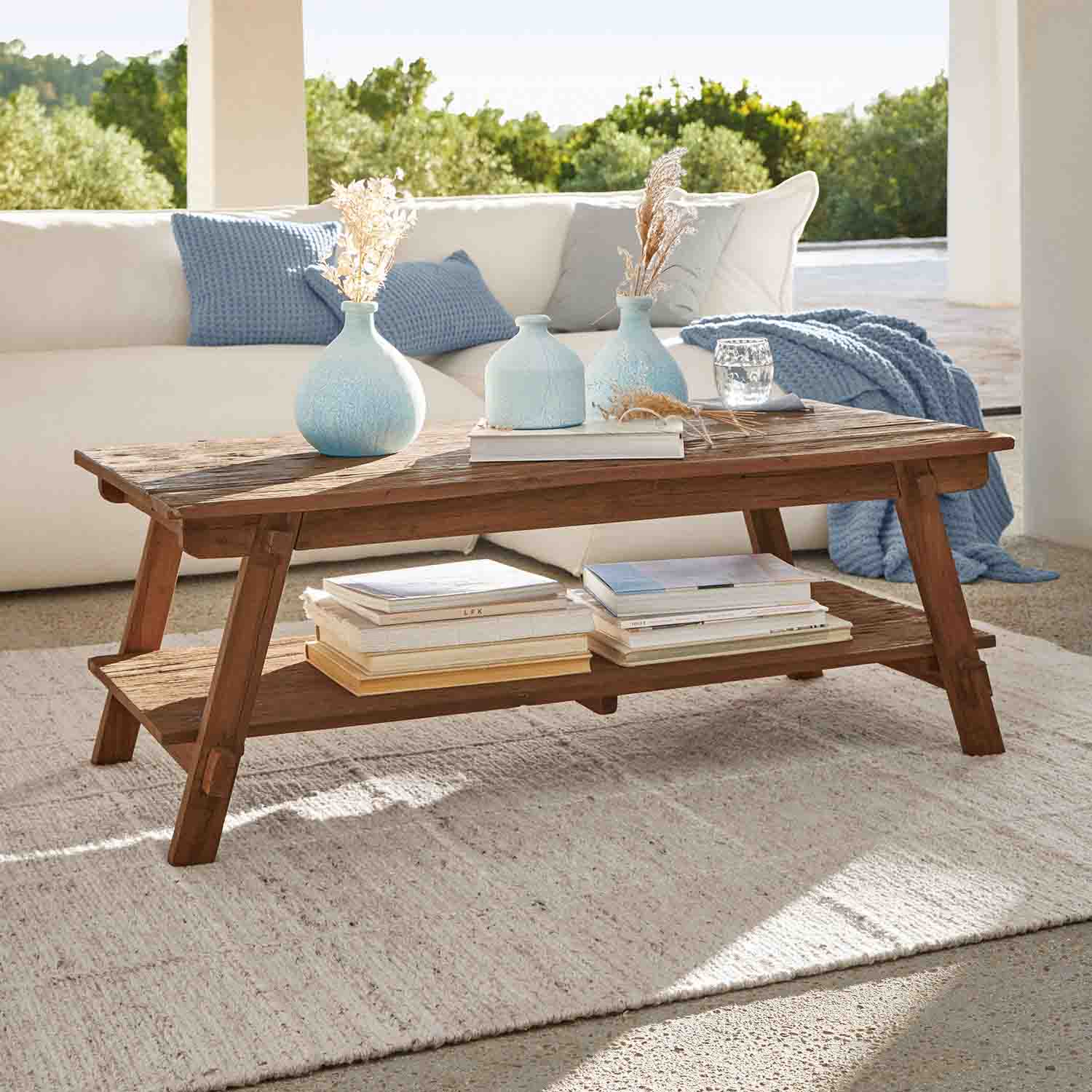 Brauner Akazienholz-Couchtisch mit Ablage und blauen Dekovasen in hellem Wohnzimmer