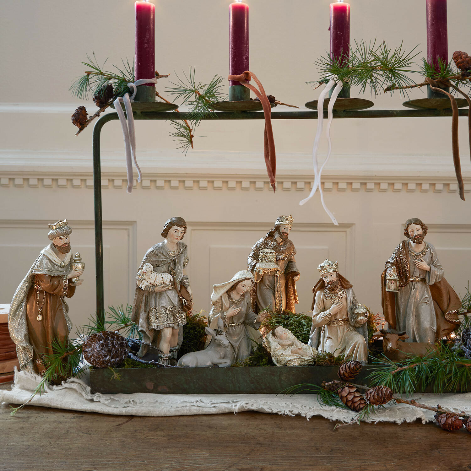 Krippenfiguren 9er Set Caprinas Krippenfiguren in natürlichen Farben mit roten Kerzen und grünen Zweigen als Weihnachtsdekoration