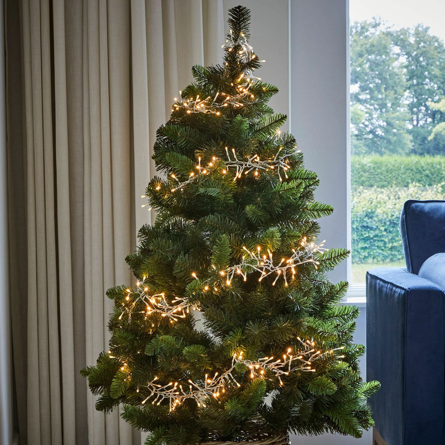 Künstlicher grüner Weihnachtsbaum mit warmweißen LED-Lichterketten im modernen Wohnzimmer