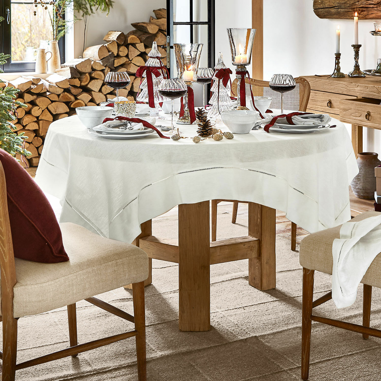 Holztisch mit weißem Leinentischdecke und festlicher Dekoration in rustikalem Raum